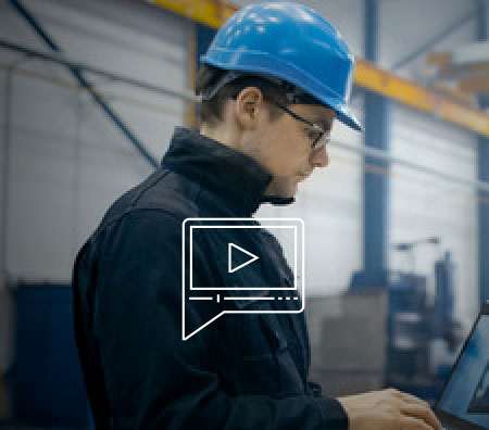 Image of frontline worker with blue hard hat working on a laptop computer.